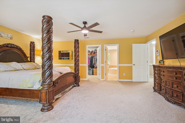 carpeted bedroom featuring connected bathroom, a walk in closet, a closet, and ceiling fan