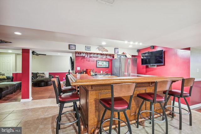 bar with stainless steel fridge and light tile patterned floors