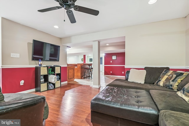 living room featuring ceiling fan, bar area, and hardwood / wood-style floors