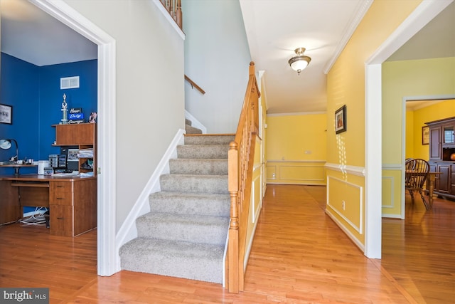 stairway with crown molding and wood-type flooring