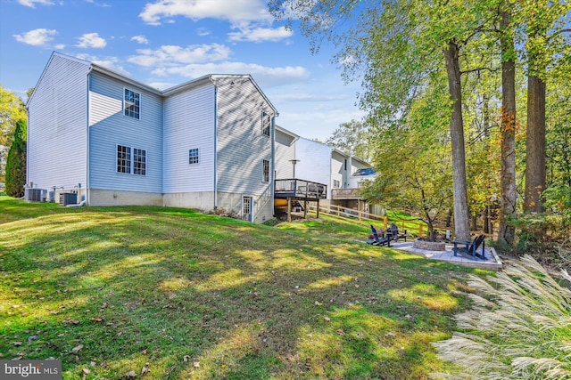 rear view of property with an outdoor fire pit, a deck, central air condition unit, and a lawn