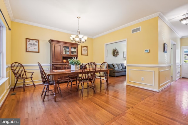 dining area with ornamental molding, hardwood / wood-style flooring, and an inviting chandelier