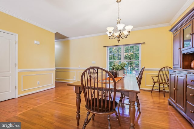 dining room with a chandelier, crown molding, and light wood-type flooring