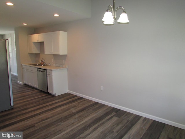 kitchen featuring dark wood-type flooring, appliances with stainless steel finishes, decorative light fixtures, and white cabinets