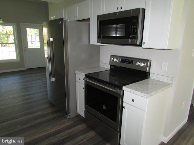 kitchen with appliances with stainless steel finishes, white cabinetry, and dark hardwood / wood-style floors