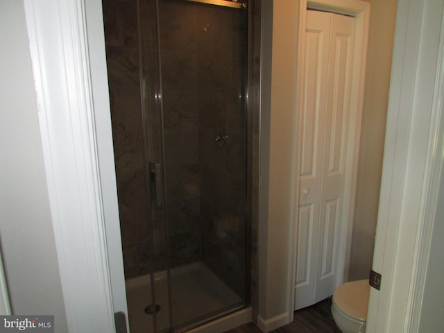 bathroom with a shower with door, toilet, and hardwood / wood-style flooring