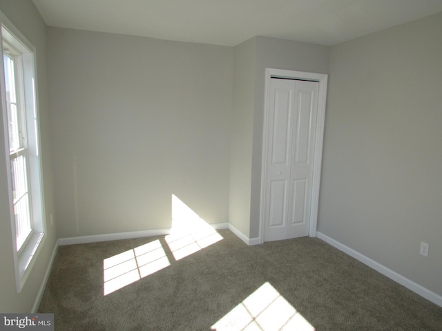 empty room featuring dark carpet and plenty of natural light