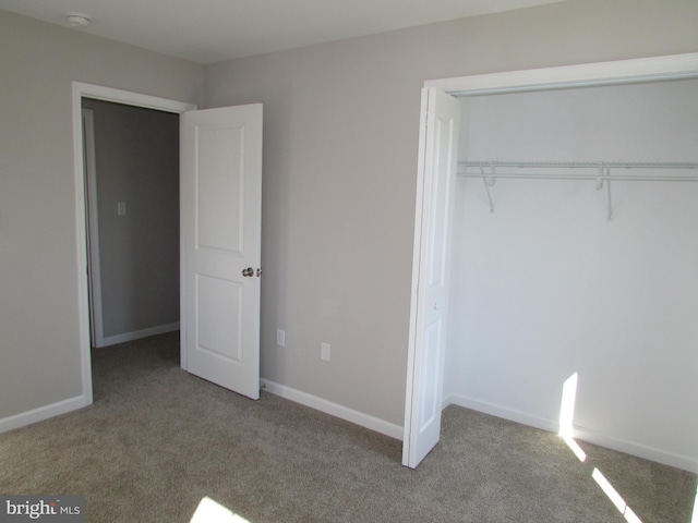 unfurnished bedroom with light carpet and a closet