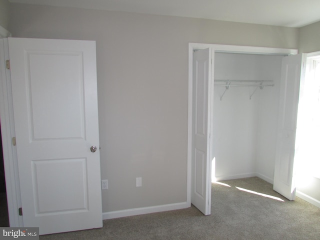 unfurnished bedroom with a closet and light carpet