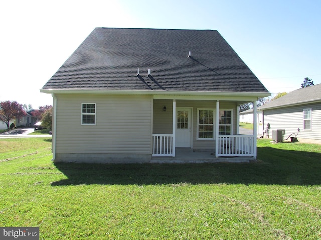 rear view of house with covered porch, central AC, and a lawn