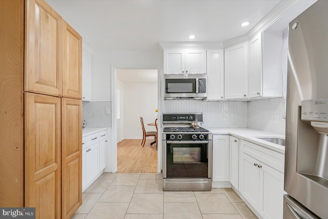 kitchen with decorative backsplash, white cabinetry, appliances with stainless steel finishes, and light tile patterned floors