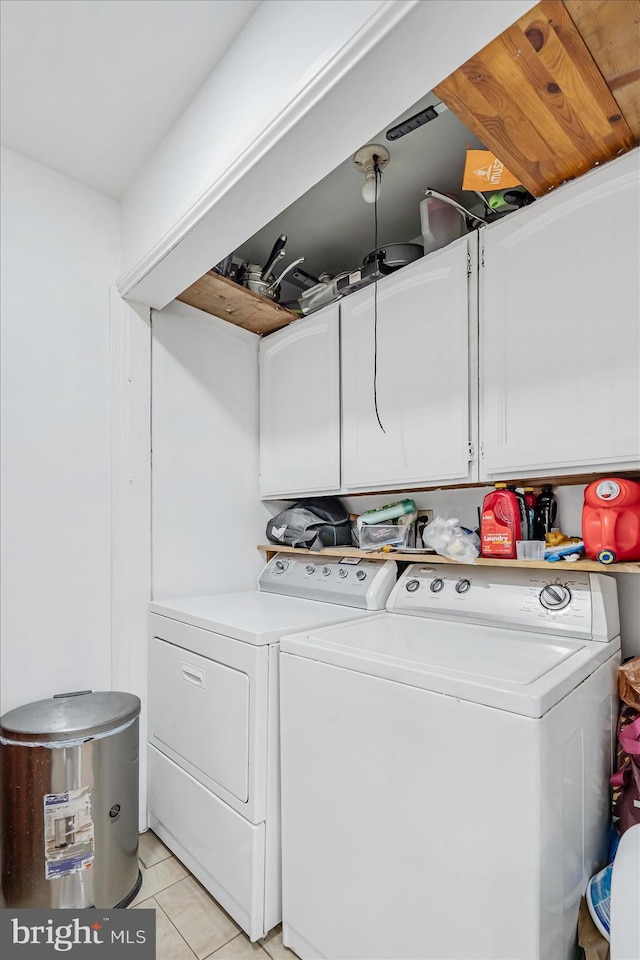 laundry room with light tile patterned floors, cabinets, and independent washer and dryer