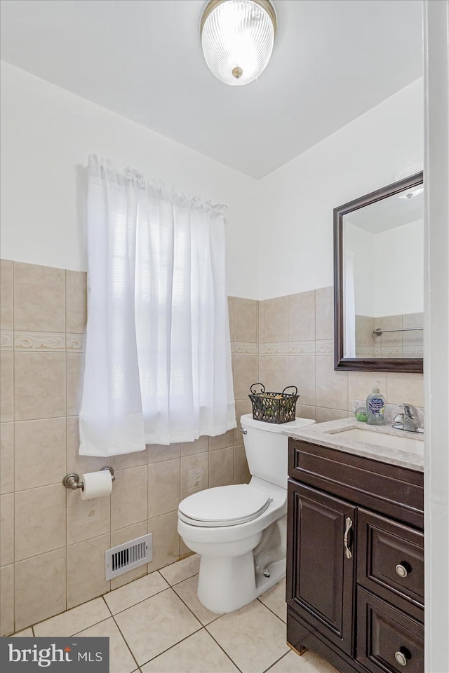 bathroom with vanity, toilet, tile walls, and tile patterned floors