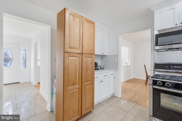 kitchen featuring appliances with stainless steel finishes, light brown cabinetry, tasteful backsplash, white cabinets, and light hardwood / wood-style floors