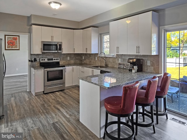 kitchen featuring appliances with stainless steel finishes, white cabinets, sink, and dark wood-type flooring