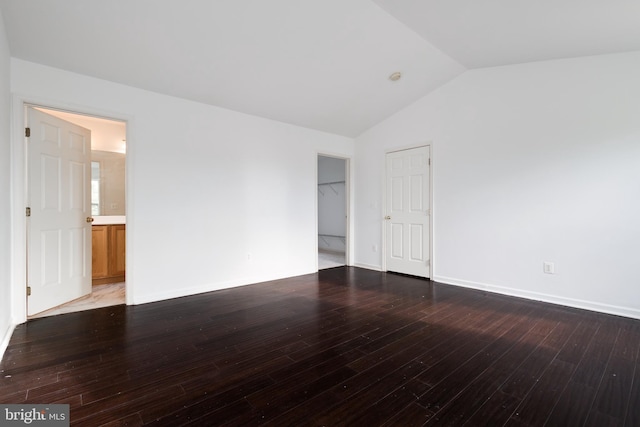 spare room with vaulted ceiling and dark hardwood / wood-style flooring