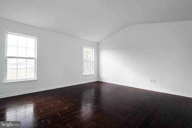 spare room featuring dark wood-type flooring and lofted ceiling