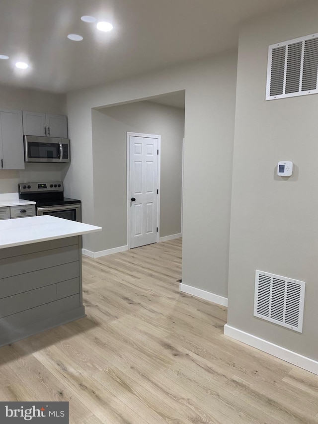 kitchen featuring gray cabinets, stainless steel appliances, and light wood-type flooring