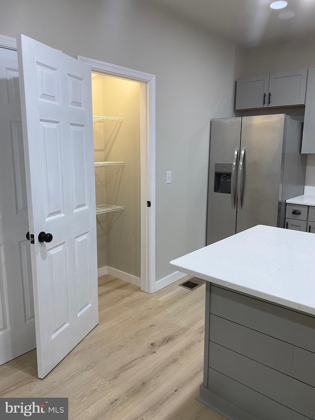 kitchen featuring stainless steel refrigerator with ice dispenser, light wood-type flooring, and gray cabinets