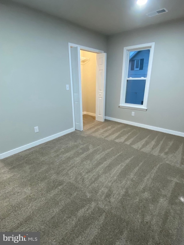 unfurnished room featuring dark colored carpet