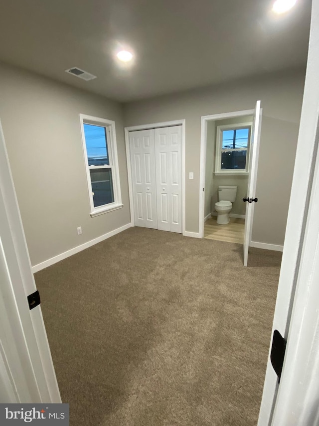 unfurnished bedroom with connected bathroom and carpet floors