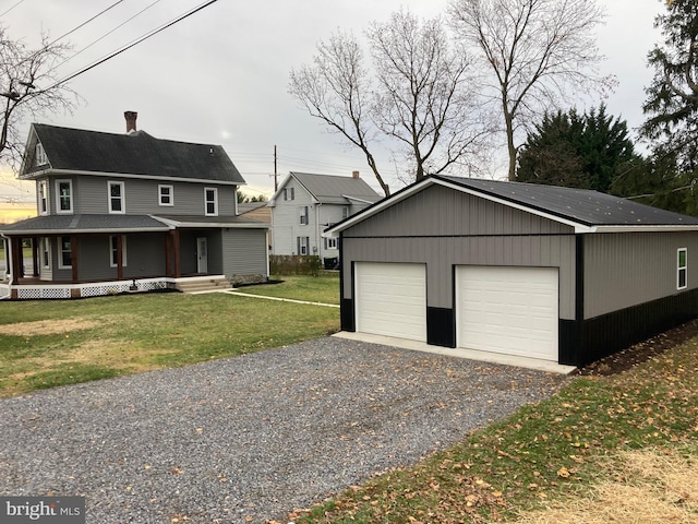 garage featuring covered porch and a yard