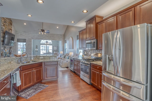 kitchen with ceiling fan, appliances with stainless steel finishes, vaulted ceiling, light hardwood / wood-style floors, and sink