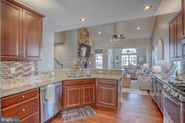 kitchen featuring kitchen peninsula, stainless steel appliances, wood-type flooring, sink, and ceiling fan