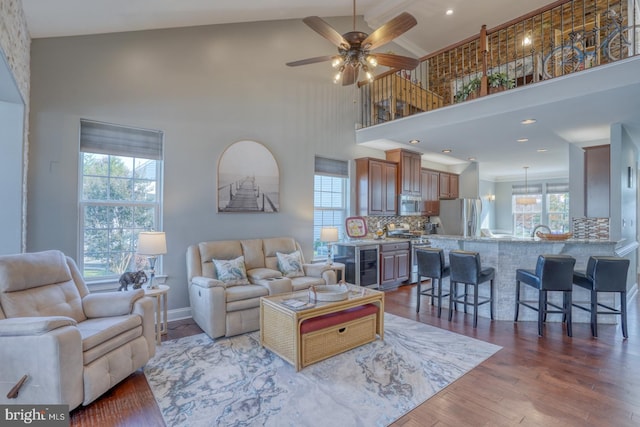 living room featuring beverage cooler, dark hardwood / wood-style floors, high vaulted ceiling, and ceiling fan