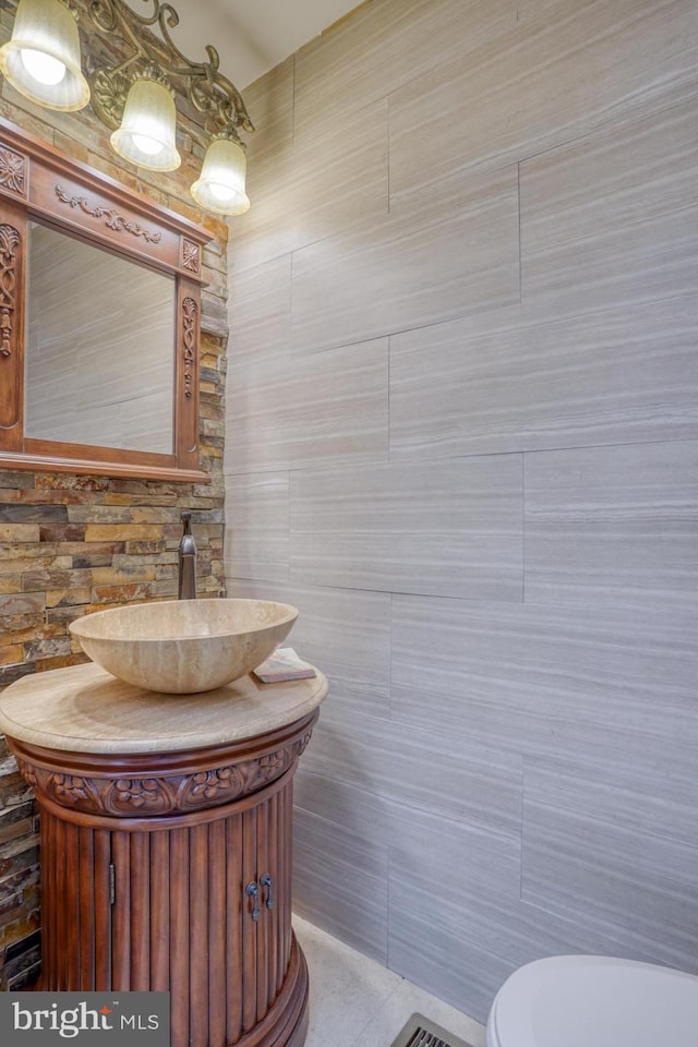 bathroom featuring tile walls, vanity, and toilet