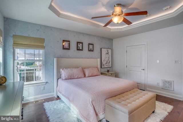 bedroom with ceiling fan, a tray ceiling, and dark hardwood / wood-style flooring