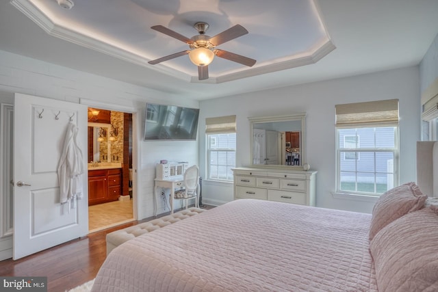 bedroom with ceiling fan, a raised ceiling, multiple windows, and light wood-type flooring