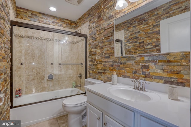 full bathroom with vanity, bath / shower combo with glass door, toilet, and tile patterned floors