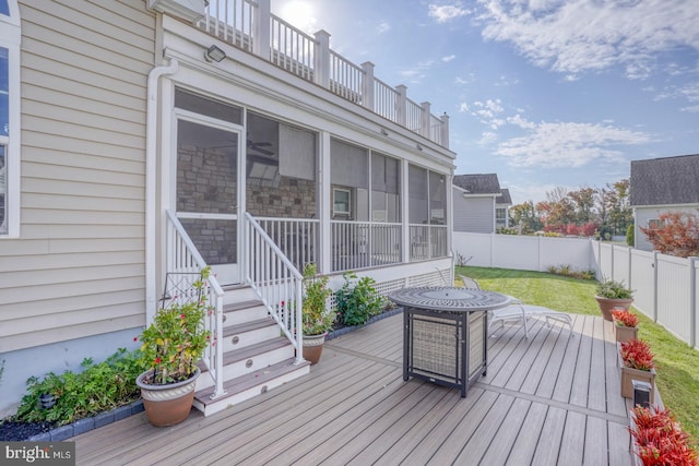 wooden deck featuring a lawn and a sunroom