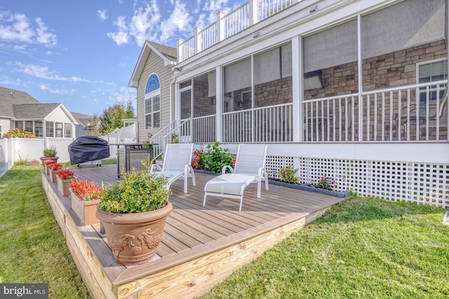 wooden terrace featuring a yard, a sunroom, and a grill