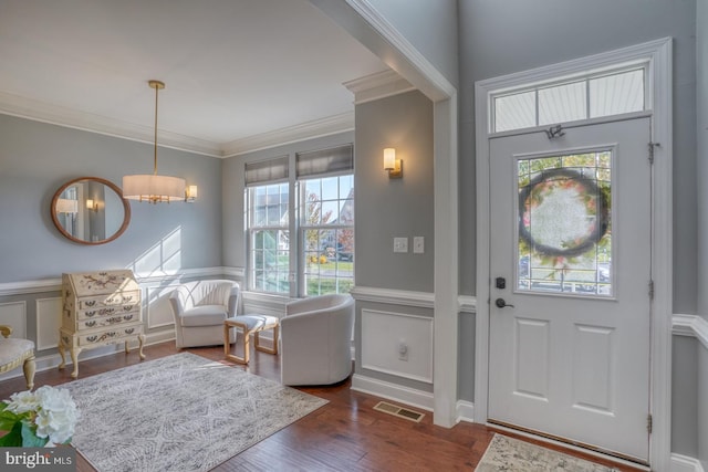 entryway with crown molding, dark hardwood / wood-style floors, a healthy amount of sunlight, and a chandelier