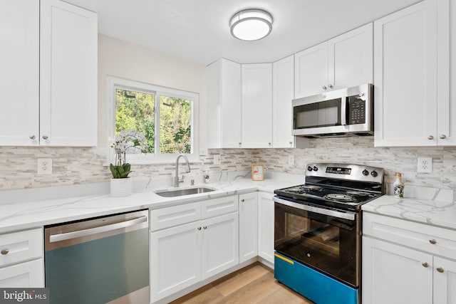 kitchen with sink, white cabinetry, stainless steel appliances, and light hardwood / wood-style floors