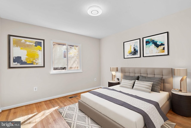 bedroom featuring baseboards, visible vents, and wood finished floors