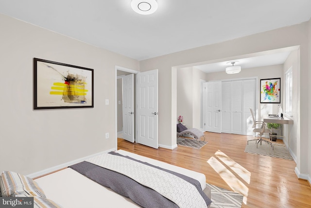 bedroom with a closet, light wood-style flooring, and baseboards