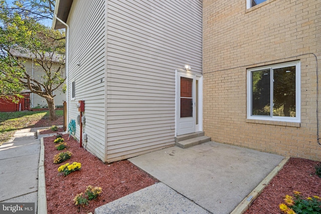 entrance to property featuring a patio and brick siding