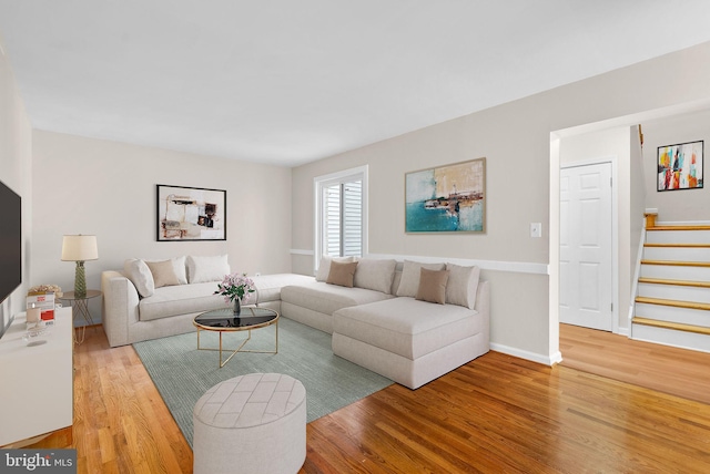 living room with wood finished floors, baseboards, and stairs
