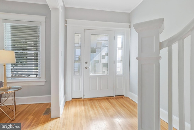 entryway with ornamental molding and light wood-type flooring