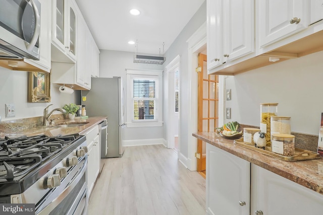 kitchen with light hardwood / wood-style flooring, sink, light stone countertops, white cabinetry, and appliances with stainless steel finishes