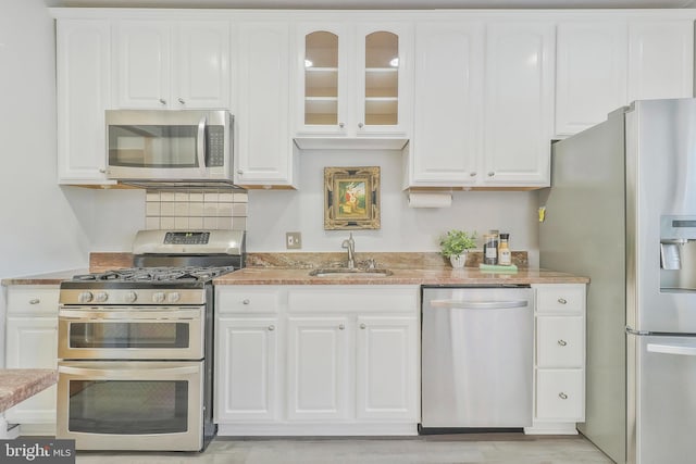 kitchen featuring stainless steel appliances, sink, white cabinetry, light hardwood / wood-style floors, and tasteful backsplash