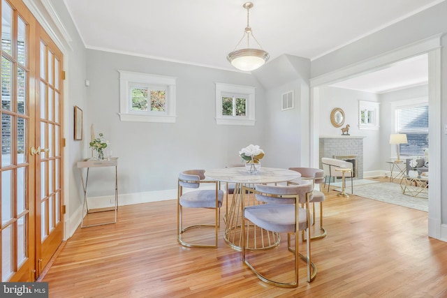 dining area with ornamental molding, light hardwood / wood-style flooring, and a fireplace