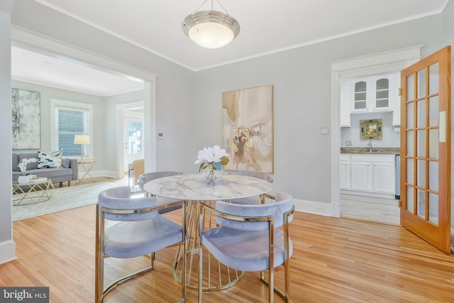 dining area featuring light hardwood / wood-style floors, ornamental molding, and sink