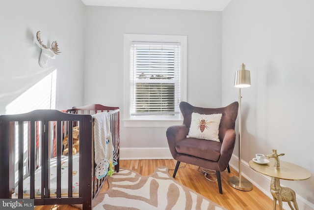 bedroom featuring a nursery area and light hardwood / wood-style flooring