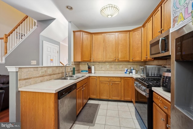 kitchen featuring sink, stainless steel appliances, backsplash, kitchen peninsula, and light tile patterned flooring