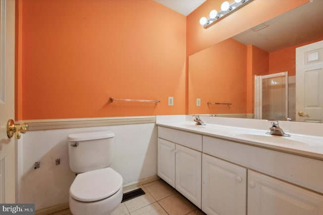 bathroom with toilet, vanity, tile patterned floors, and a shower with shower door