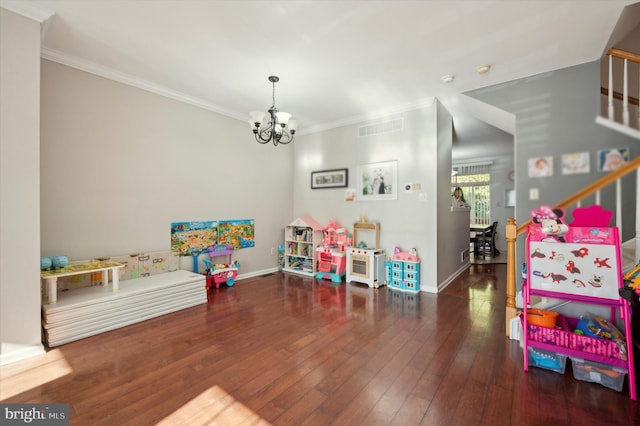 playroom featuring dark hardwood / wood-style floors, crown molding, and a chandelier